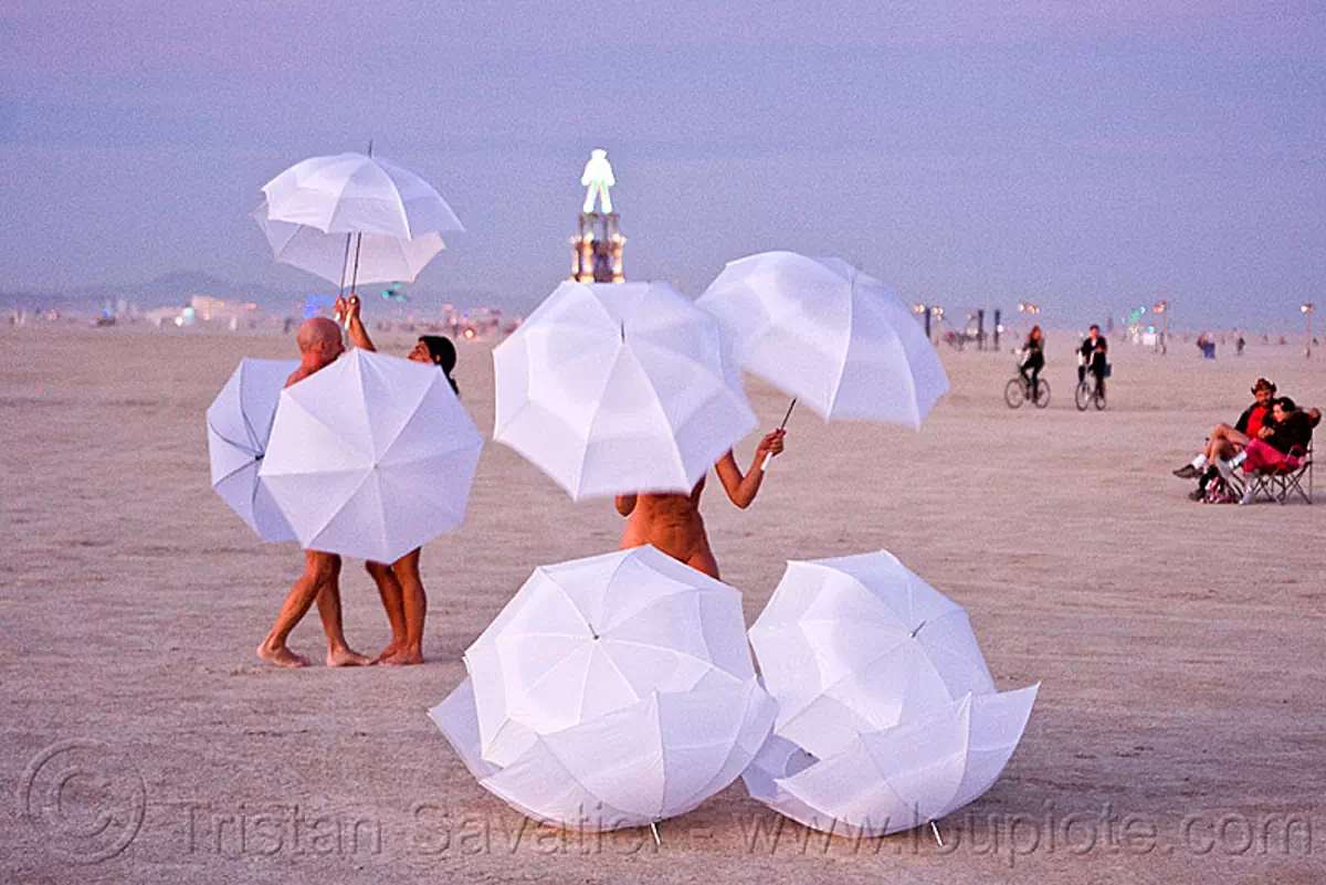 the umbrella-man performing at dawn - burning man 2010, burning man festival, performance, the man, u-man, umbrella man, white umbrellas, stock photo