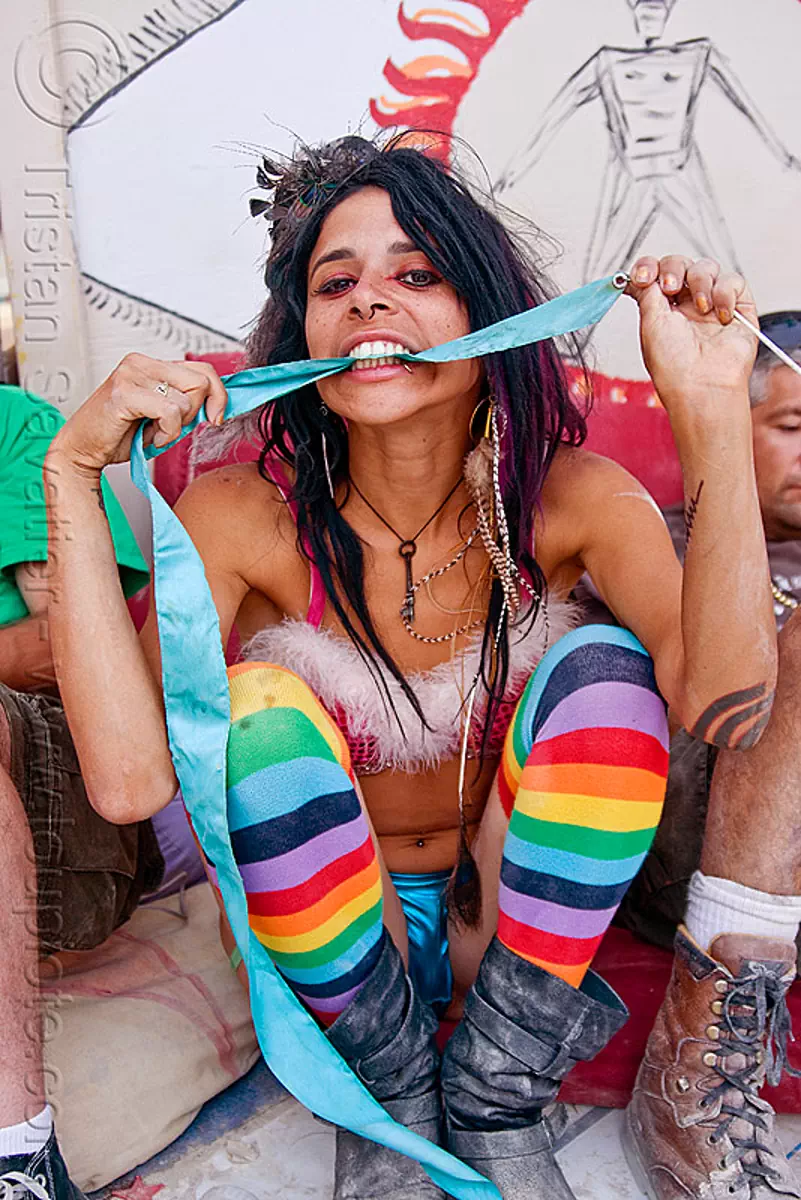 rainbow tights, biting, bitting, blue ribbon, burning man festival, center camp, flowing ribbon, mumu, rainbow colors, rainbow stockings, squatting, stock photo
