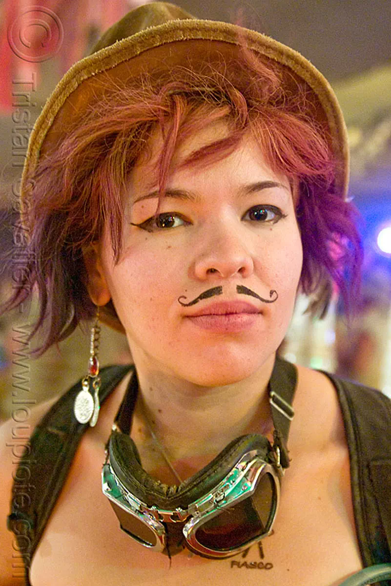 girl with fake mustache, asian woman, burning man festival, center camp, fake moustache, false moustache, false mustache, goggles, hat, makeup, mustaches, redhead, roxy doll, stock photo