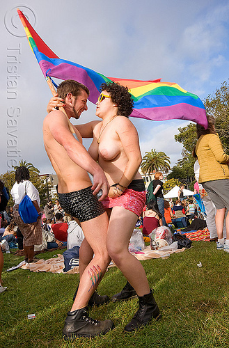 couple dancing with rainbow flag, dancing, flag pole, gay pride festival, man, rainbow flag, topless, woman