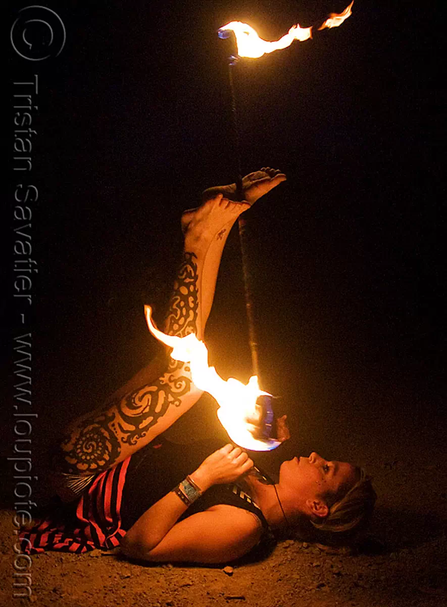 leg tattoo - lily spinning fire staff with feet (san francisco), fire dancer, fire dancing, fire performer, fire spinning, flame, long exposure, night, tattooed, stock photo