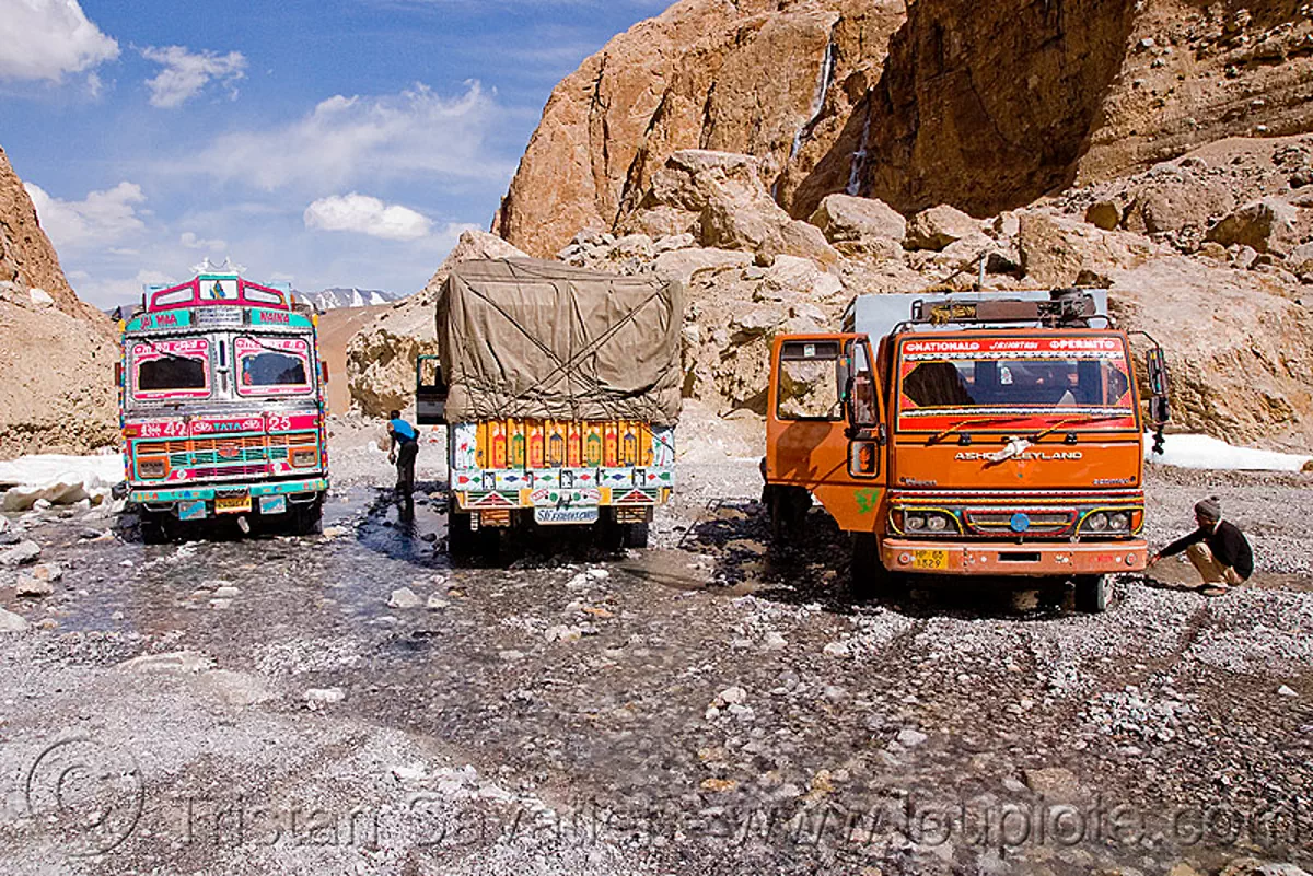 large nullah in the canyon before pang - manali to leh road (india), ladakh, mountains, river bed, soft gravel, stream, stuck, traffic jam, trucks, water, stock photo
