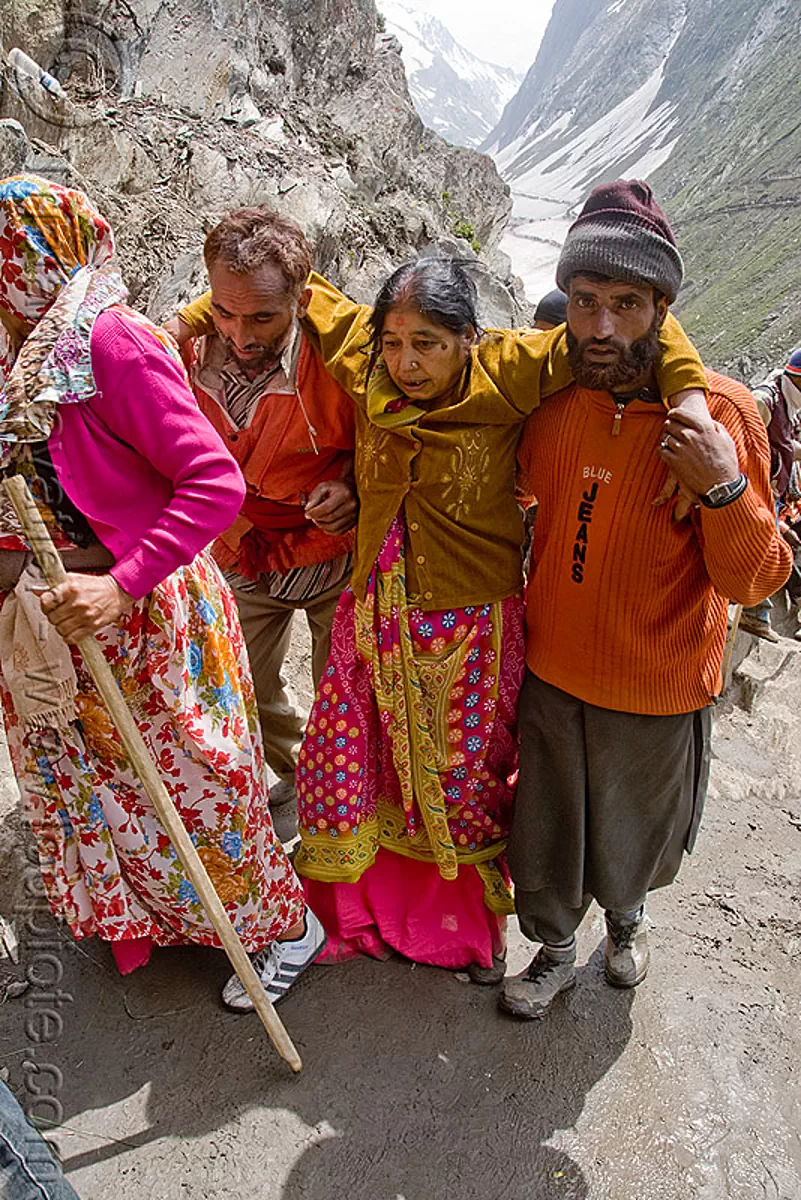 men helping exhausted woman on trail - amarnath yatra (pilgrimage) - kashmir, amarnath cave, mountain trail, mountains, pilgrims, saree, sari, trekking, yatris, अमरनाथ गुफा, stock photo