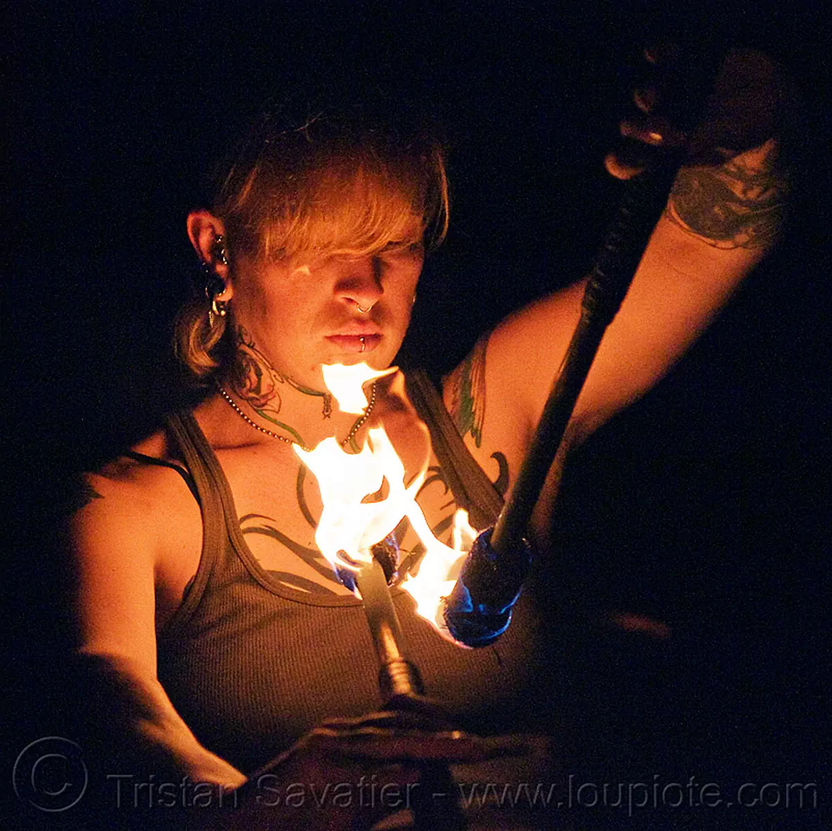looking at her fire staves - leah, fire dancer, fire dancing, fire performer, fire spinning, fire staffs, flame, night, tattoo, tattooed