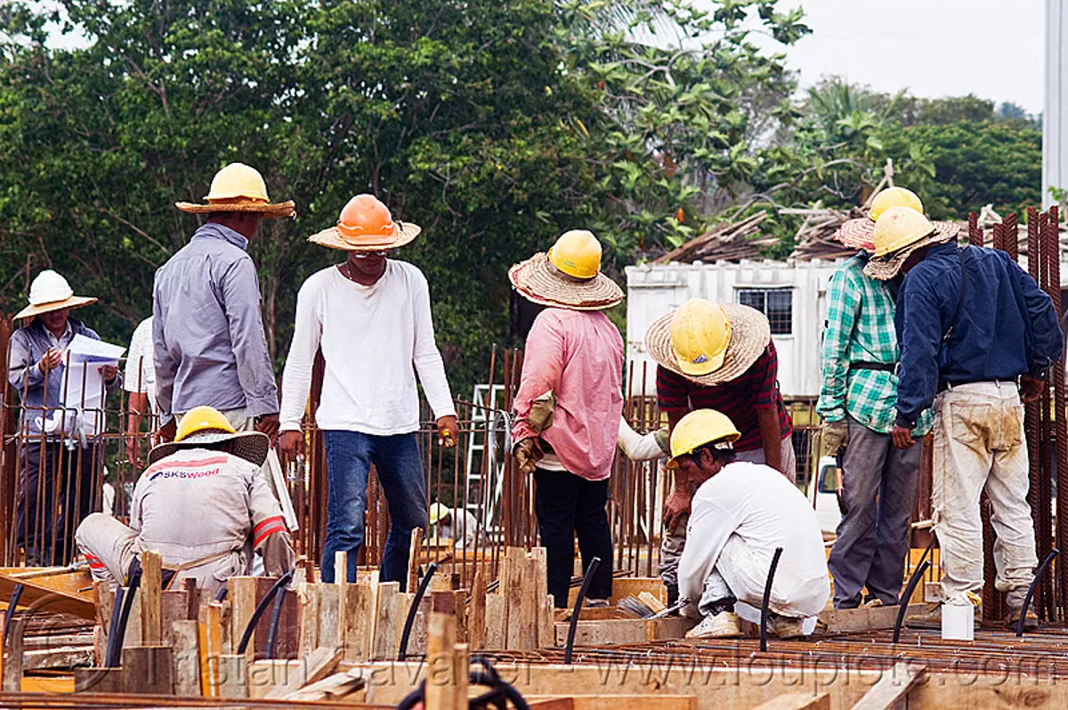 construction workers with straw hats and safety helmets, building construction, concrete forms, concrete wall forms, construction site, formwork, lumber, man, miri, rebars, safety helmet, standing, straw hat, sun hat, timber, stock photo