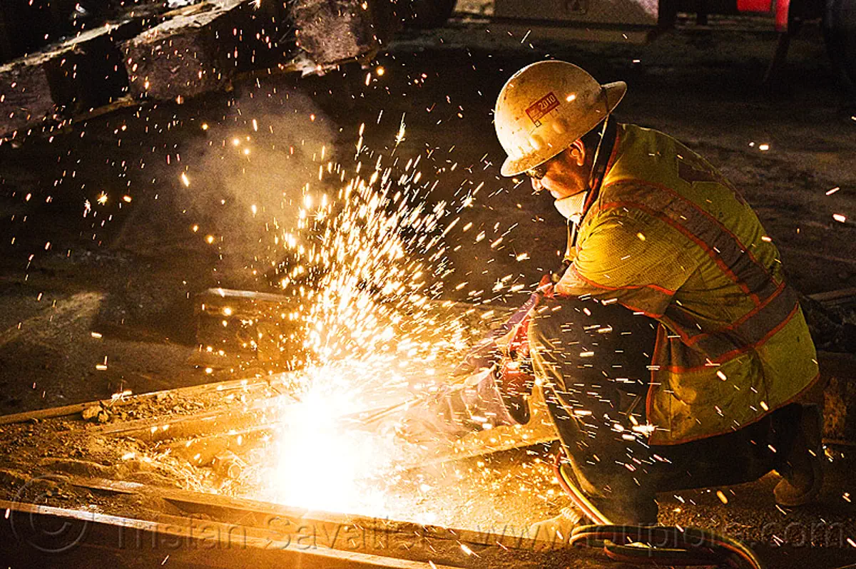 railroad worker cutting a track rail with a oxy acetylene railway torch light