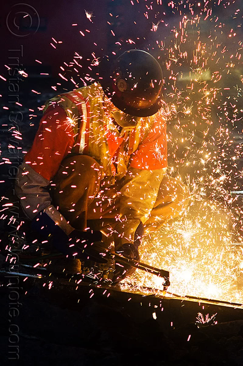 oxy-acetylene cutting torch, dust mask, light rail, man, muni, night, ntk, oxy-fuel cutting, railroad construction, railroad tracks, rails, reflective vest, safety helmet, safety vest, san francisco municipal railway, sparks, track maintenance, track work, welder, worker