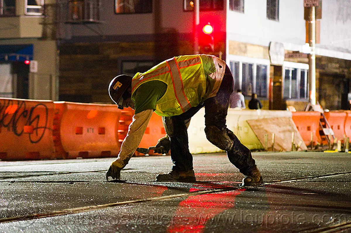 troweling the concrete, backlight, cement, light rail, man, muni, night, ntk, railroad construction, railroad tracks, rails, reflective vest, safery vest, safety helmet, san francisco municipal railway, track maintenance, track work, trowel, worker, stock photo