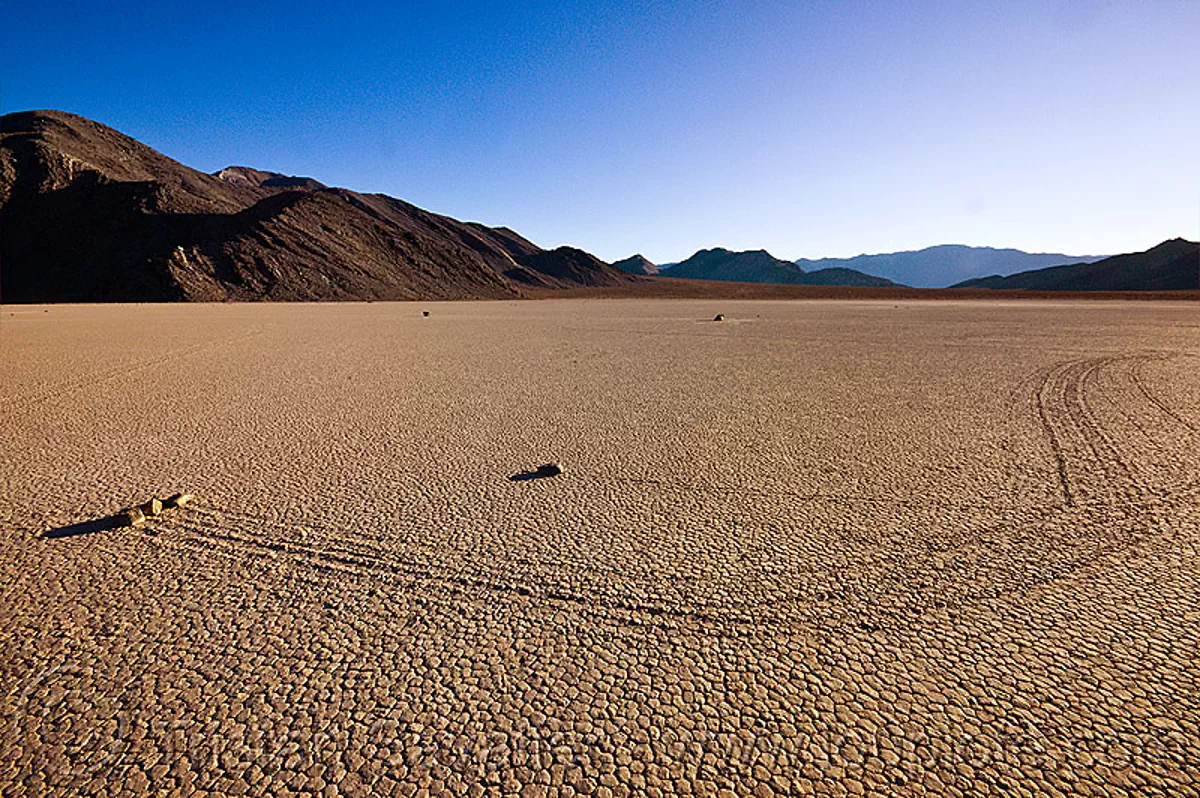 sailing stones travelling together on the racetrack (death valley), cracked mud, desert, dry lake, dry mud, mountains, moving rocks, racetrack playa, sliding rocks, tracks, stock photo