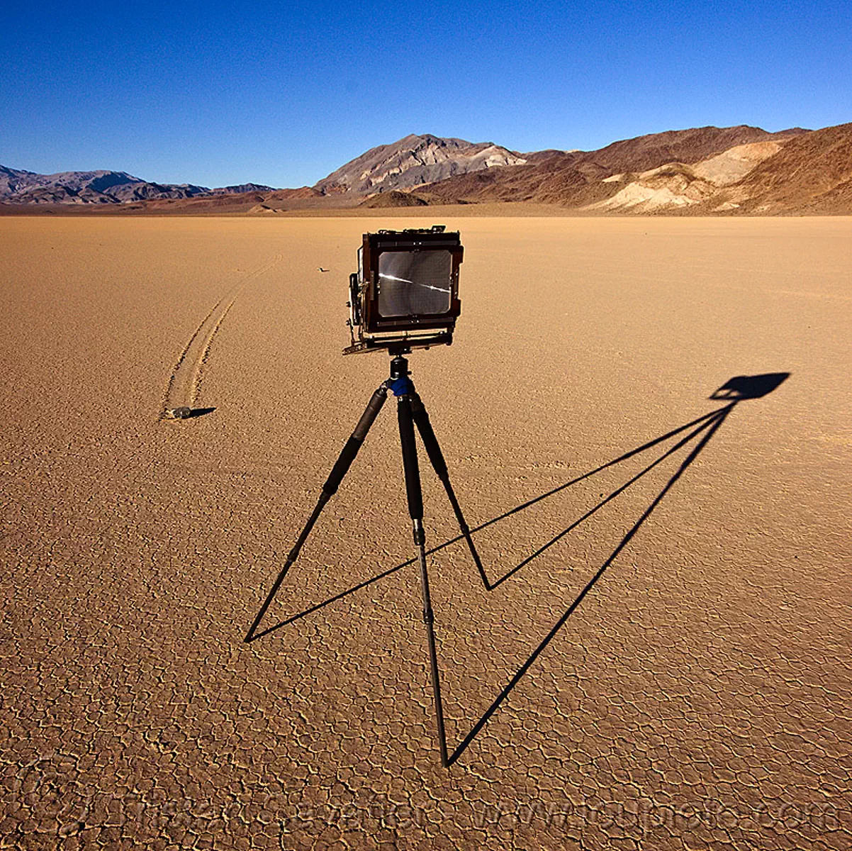 photographing a sailing stone on the racetrack (death valley), cracked mud, desert, dry lake, dry mud, film camera, large format, mountains, moving rock, photographic chamber, racetrack playa, shadow, sliding rock, track, tripod, stock photo