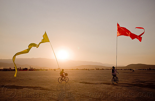 burning man - bicycles with streamer flags, bicycle flags, bicycles, poles, red, riding, streamer flags, streamers, sunset, yellow