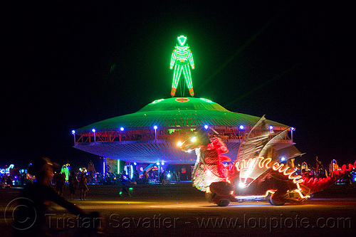 burning man - the man on the giant ufo at night, burning man art cars, burning man at night, flying saucer, glowing, mutant vehicles, the man, ufo, unidentified art car