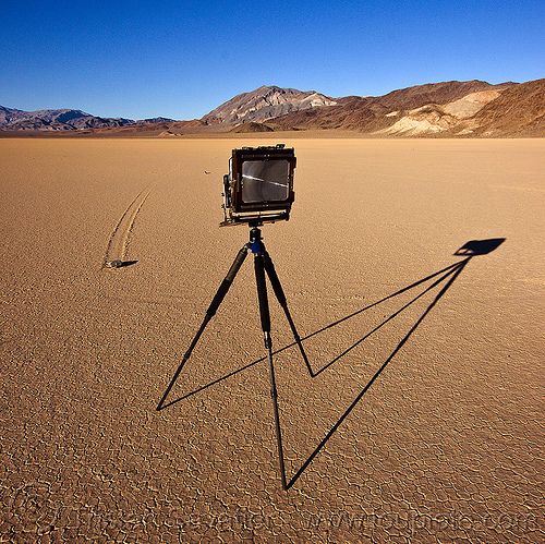 chamber camera on tripod in front of a sailing stone on the racetrack - death valley, chamber camera, death valley, dry lake, dry mud, film camera, landscape, large format, mountains, racetrack playa, rock, sailing stones, sliding rocks, tripod