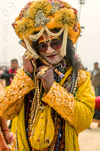 drag queen hindu guru in yellow costume and decorated turban - kumbh mela (india), beads, costume, decorated, dressed-up, finger rings, flute, guru, headdress, hindu pilgrimage, hinduism, kumbh mela, makeup, man, necklaces, sunglasses, tilak, tilaka, turban, yellow