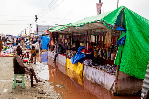 flooded market stalls - kumbh mela 2013 (india), flood, flooded, hindu pilgrimage, hinduism, kumbh mela, man, merchant, shopkeeper, sitting, souvenir shop, stalls, street market, street seller, tarp, vendor