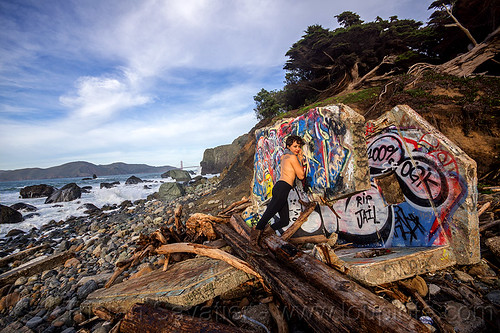 graffiti on concrete ruins, concrete, driftwood, graffiti, ocean, rocks, ruins, sea, seashore, tree logs, trees, woman, yassmine
