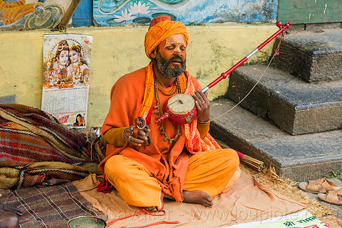 hindu devotee singing mantra and playing musical instrument (nepal), baba, beard, bhagwa, cross-legged, headwear, hindu, hinduism, kathmandu, maha shivaratri, man, musical instrument, pashupatinath, playing music, sadhu, saffron color, sitting, tilak, tilaka