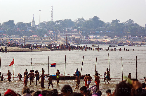 hindu pilgrims on sand bar in the ganges river at sangam - kumbh mela 2013 (india), bathing pilgrims, crowd, dawn, fence, flags, ganga, ganges river, hindu pilgrimage, hinduism, holy bath, holy dip, kumbh mela, nadi bath, paush purnima, ritual bath, river bank, river bathing, river boats, river island, sand bar, silhouettes, triveni sangam