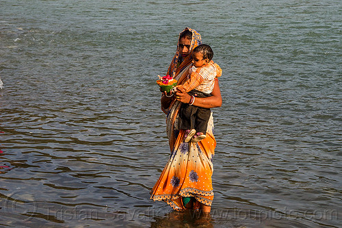 hindu woman and small child in ganges river with offering (india), baby, bathing pilgrims, child, ganga, ganges river, ghats, hinduism, holy bath, holy dip, indian woman, kid, mother, nadi bath, offering, rishikesh, river bathing, saree, sari, toddler, triveni ghat, wading