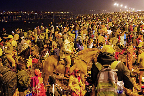horse police patrolling the crowd of hindu pilgrims gathering at kumbh mela 2013 (india), cops, crowd control, fence, ganga, ganges river, hindu pilgrimage, hinduism, holy dip, horseback riding, kumbh mela, law enforcement, men, mounted police, night, paush purnima, pilgrims, police horses, police officers, river bank, street lights, triveni sangam, women