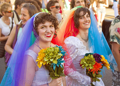 lesbian couple in rainbow color wedding dresses, bridal bouquets, brides, gay couple, gay marriage, gay pride festival, gay wedding, lesbian couple, rainbow colors, same-sex marriage, same-sex wedding, veils, wedding bouquet, wedding dresses, women