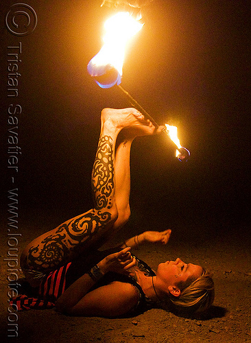 lily spinning fire staff with feet (san francisco), fire dancer, fire dancing, fire performer, fire spinning, fire staff, leg tattoo, night, spinning fire, tattooed, tattoos, woman