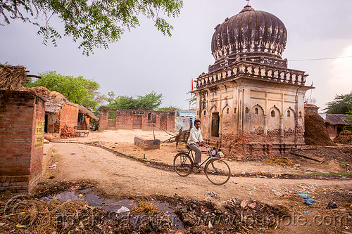 man on bicycle near old monument in indian village, bicycle, garbage, khoaja phool, man, monument, plastic trash, shrine, temple, village, खोअजा फूल