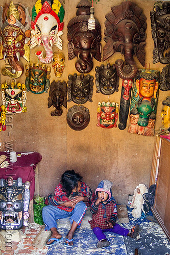 mother and her little girl sitting in souvenir shop (nepal), bhaktapur, child, daughter, ganesha, hanging, kid, little girl, masks, mother, sitting, wood carving