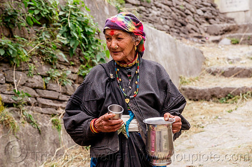 old hindu woman with jar of chai (india), chai, dhauliganga valley, ear piercing, earring, indian woman, jar, jewelry, mountains, necklaces, nose piercing, nostril piercing, old woman, raini chak lata, spice tea, stair, steps, village