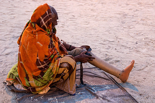 old man adjusting his prosthetic leg (india), amputated, bhagwa, hindu pilgrimage, hinduism, kumbh mela, leg amputee, man, prosthetic leg, prosthetics, saffron color, sitting