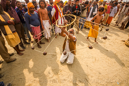 old man spinning balls with ropes (india), crowd, game, hindu pilgrimage, hinduism, indian spinning balls, kumbh mela, man, metal balls, performer, ropes, spectators