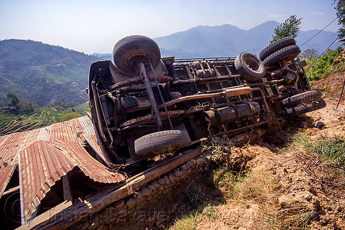 overturned truck on house roof (nepal), corrugated metal, crash, ditch, lorry accident, mountain road, overturned, rollover, tata motors, traffic accident, truck accident, underbelly, up-side-down, wreck