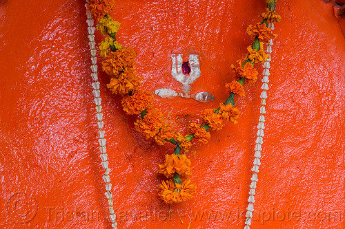 painted stone representing shiva (india), bhagwa, flowers, hinduism, marigold, necklaces, orange, rishikesh, saffron color, shiva, shrine, symbol, tilak, tilaka