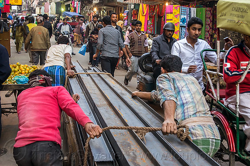 steel i-beam rails rolled on cart in street (india), construction, crowd, delhi, i-beams, men, rope, roped, steel beams, workers, working