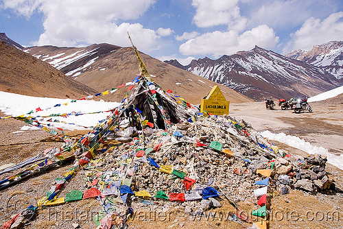 tibetan prayer flags on lachulung pass - manali to leh road (india), buddhism, lachulung pass, lachulungla, ladakh, motorcycle touring, motorcycles, mountain pass, mountains, prayer flags, road, royal enfield bullet, snow patches, stone cairn, tibetan