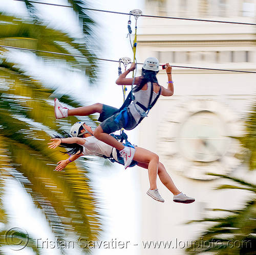 two girls riding the zip-line over san francisco, adventure, blue sky, cable line, cables, campanil, climbing helmet, clock tower, embarcadero tower, ferry building, hanging, mountaineering, moving fast, palm trees, sonia, speed, steel cable, trolley, tyrolienne, urban, women, zip line, zip wire
