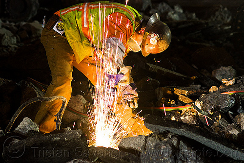 welder cutting a track rail with a oxy-acetylene torch, dust mask, high-visibility jacket, high-visibility vest, light rail, man, muni, night, ntk, oxy-acetylene cutting torch, oxy-fuel cutting, railroad construction, railroad tracks, railway tracks, reflective jacket, reflective vest, safety glasses, safety gloves, safety helmet, safety vest, san francisco municipal railway, sparks, track maintenance, track work, welder, worker, working