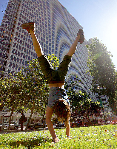 woman cartwheeling in park (san francisco), cartwheeling, catrwheel, city park, gymnastics, hirise building, jessika, lawn, trees, upside-down, woman
