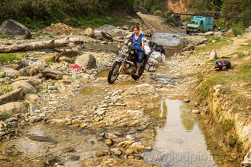 woman riding royal enfield motorcycle on dirt road (nepal), 350cc, anne-laure, bags, dirt road, fording, lorry, luggage, motorcycle touring, rider, riding, river crossing, royal enfield bullet, thunderbird, truck, unpaved, woman