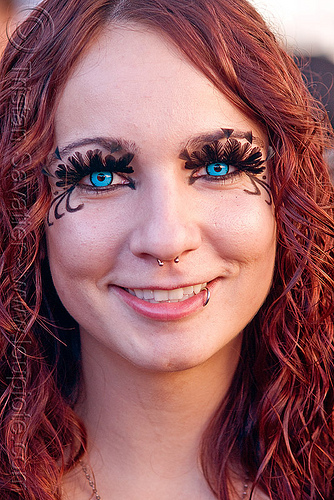 woman wiith blue color contact lenses, blue contact lenses, blue contacts, color contact lenses, eyelashes extensions, feather eyelashes, lip piercing, nose piercing, redhead, septum piercing, special effects contact lenses, theatrical contact lenses, woman