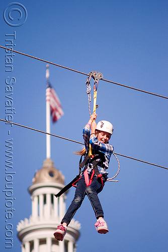 zip-line over san francisco, adventure, american flag, blue sky, cable line, cables, campanil, child, climbing helmet, clock tower, embarcadero tower, ferry building, hanging, kid, mountaineering, moving fast, speed, steel cable, trolley, tyrolienne, urban, us flag, zip line, zip wire