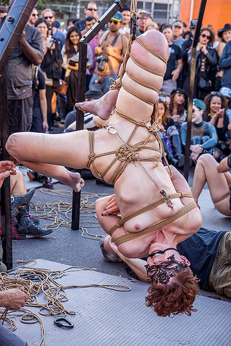 naked woman in upside down suspension bondage - folsom street fair 2015 (san francisco), carnival mask, chain, clamp, clover clamps, fetish, lace mask, masked, nude, rope bondage, suspension bondage, topless, upside down, woman