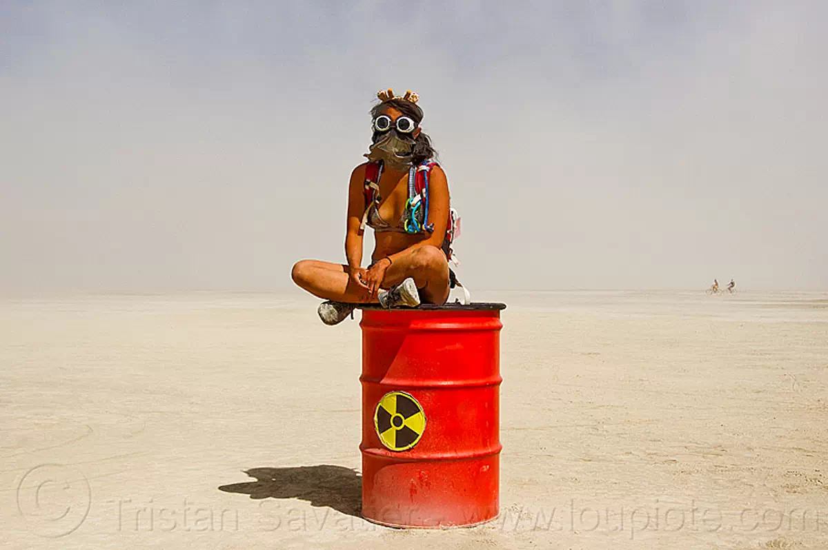 burning man - radioactive waste drum, barrel, cross-legged, drum, goggles, nuclear waste, radioactive waste, red, sitting, woman