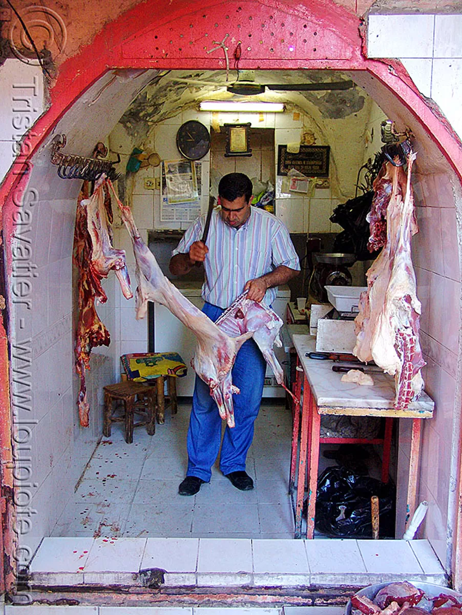 butcher in meat shop, butcher knife, carcass, carcasses, chevon, cleaver, cutting, goat meat, halal meat, hanging, hooks, kurdistan, man, mardin, meat market, meat shop, mutton, raw meat, worker