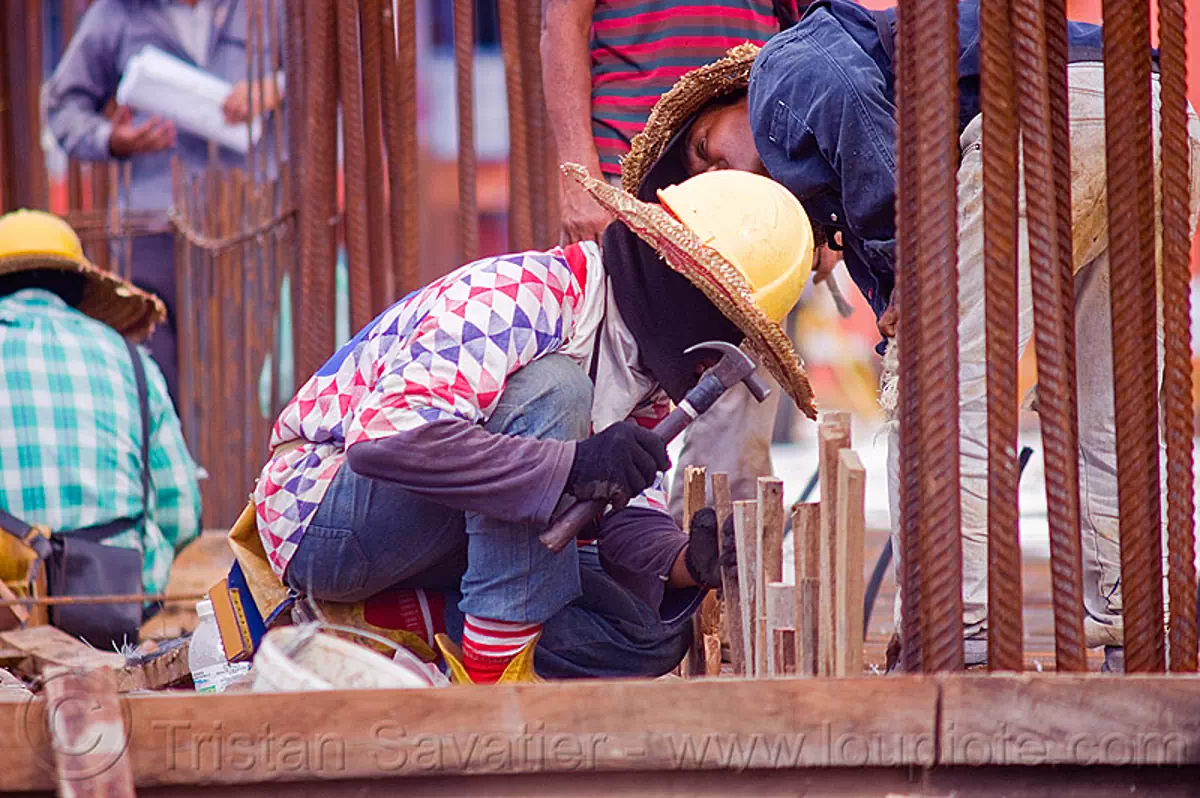 construction worker building concrete formwork, borneo, building construction, concrete forms, concrete wall forms, construction site, construction workers, face mask, formwork, hammer, lumber, malaysia, man, miri, rebars, safety helmet, squating, straw hat, sun hat, timber, working