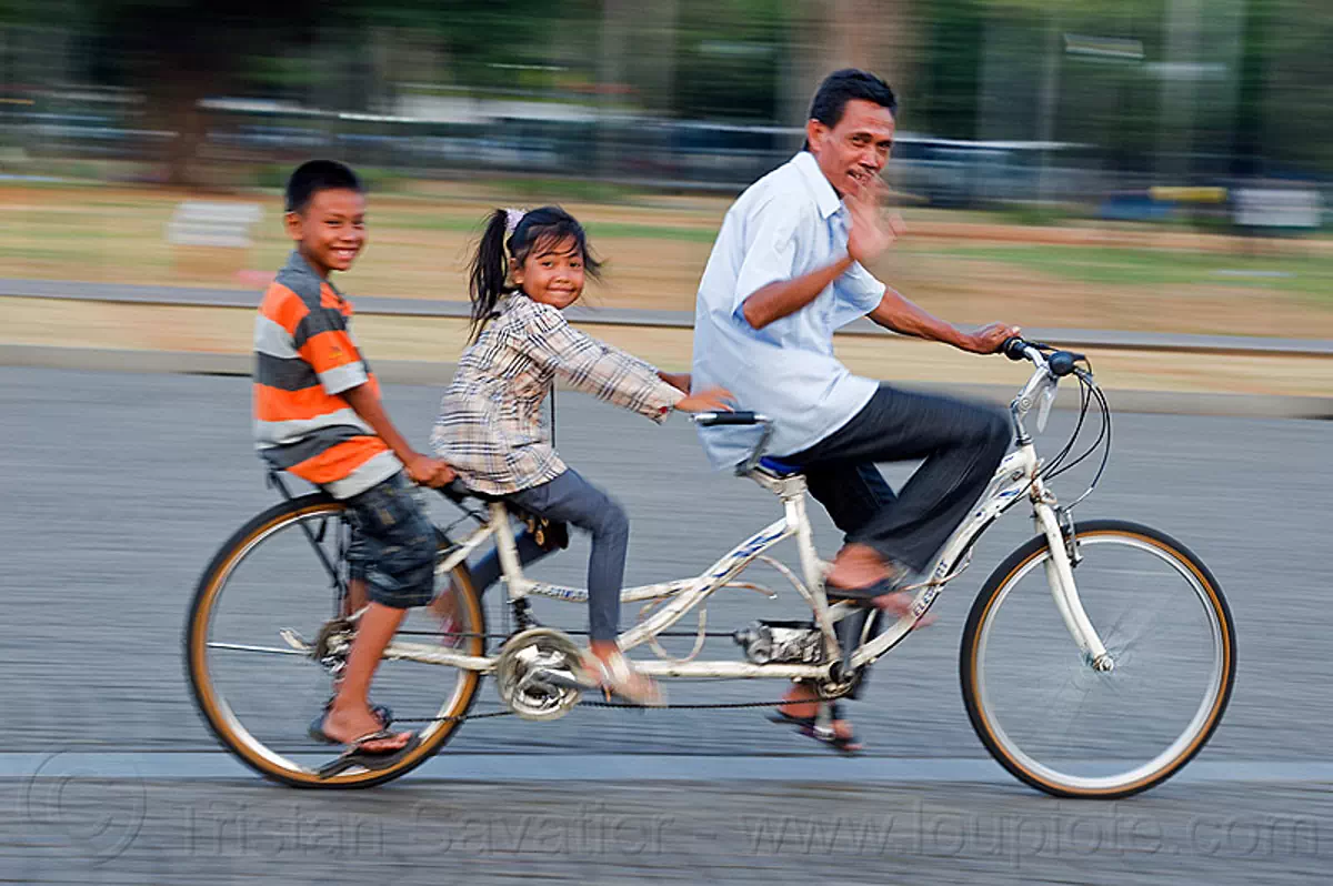 dad and kids riding tandem bicycle