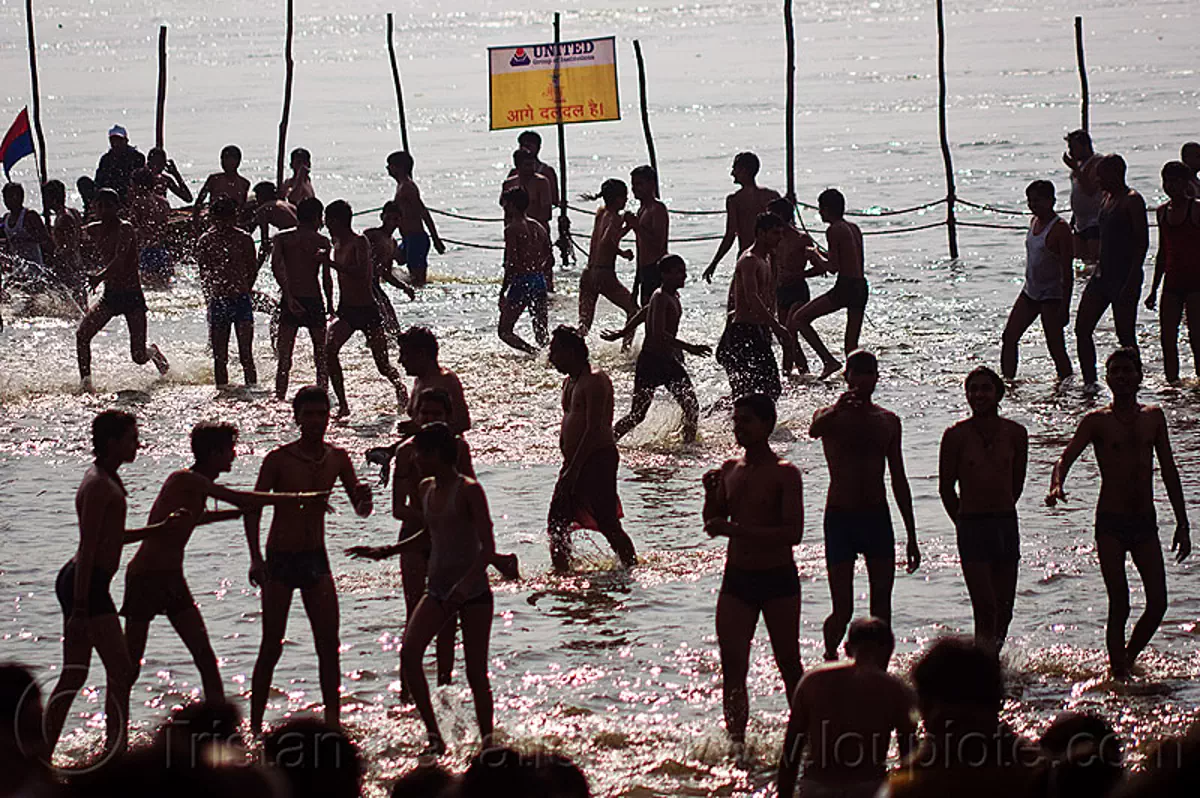 hindu boys running and dancing in the ganges river at sangam - kumbh mela 2013 (india), backlight, bathing pilgrims, boys, crowd, dancing, dawn, fence, ganga, ganges river, hindu pilgrimage, hinduism, holy bath, holy dip, kumbh mela, men, nadi bath, paush purnima, ritual bath, river bathing, river boats, running, silhouettes, triveni sangam