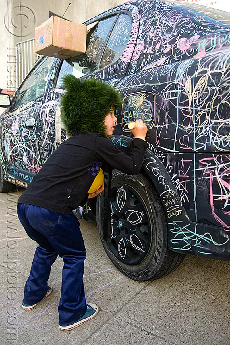 kid chalk writing on car - burning man decompression 2009 (san francisco), black car, chalk writing, child, graffiti, kid, street art, vandalism