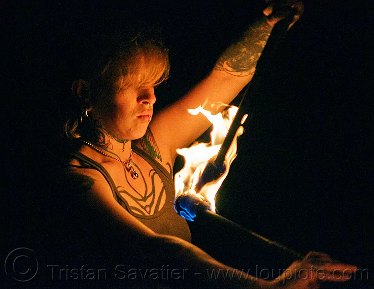 looking at fire staves - leah, fire dancer, fire dancing, fire performer, fire spinning, fire staffs, fire staves, leah, night, tattooed, tattoos, woman