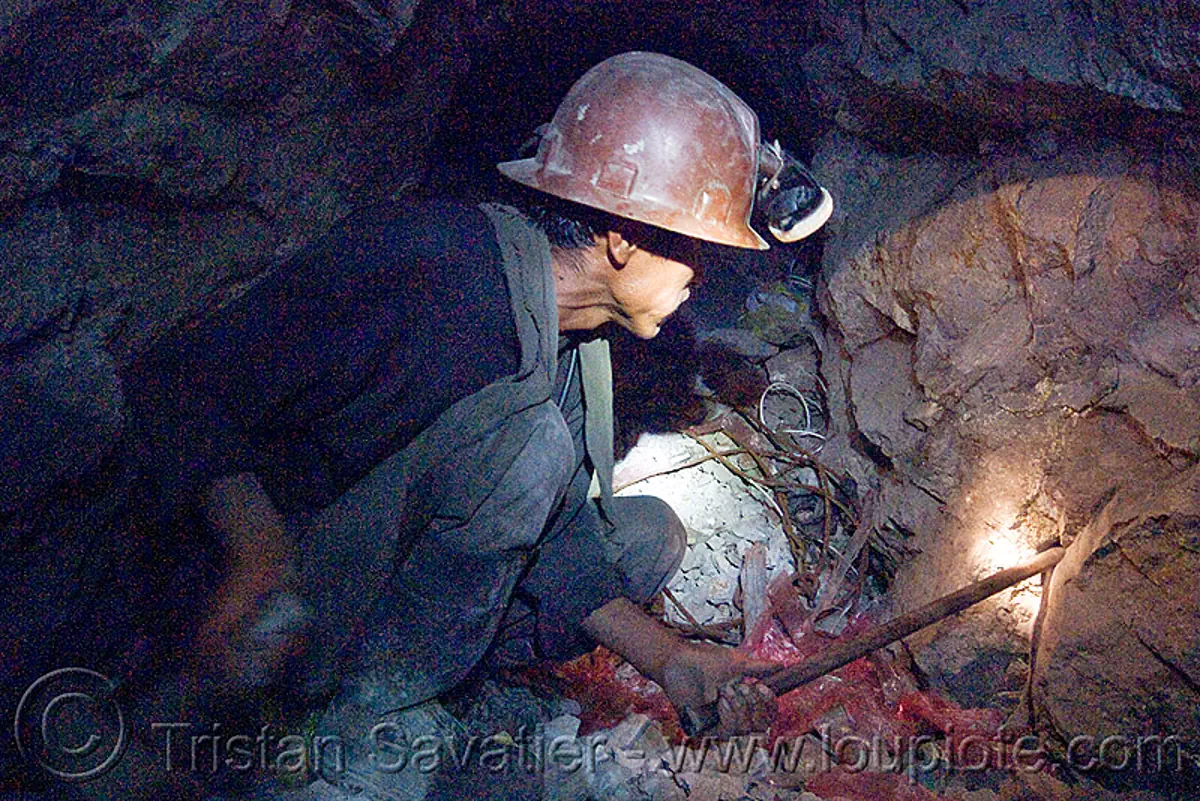 miner hammering chisel to drill blasting hole, bolivia, cerro rico, chisel, drilling, hammer, man, mina candelaria, mine tunnel, mine worker, miner, mining, potosí, safety helmet, squatting, underground mine, working